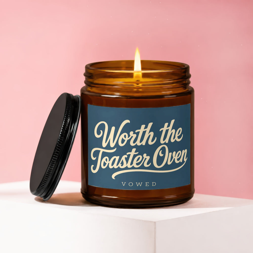 Amber jar candle with lit wick, "Worth the Toaster Oven" and "VOWED" text.