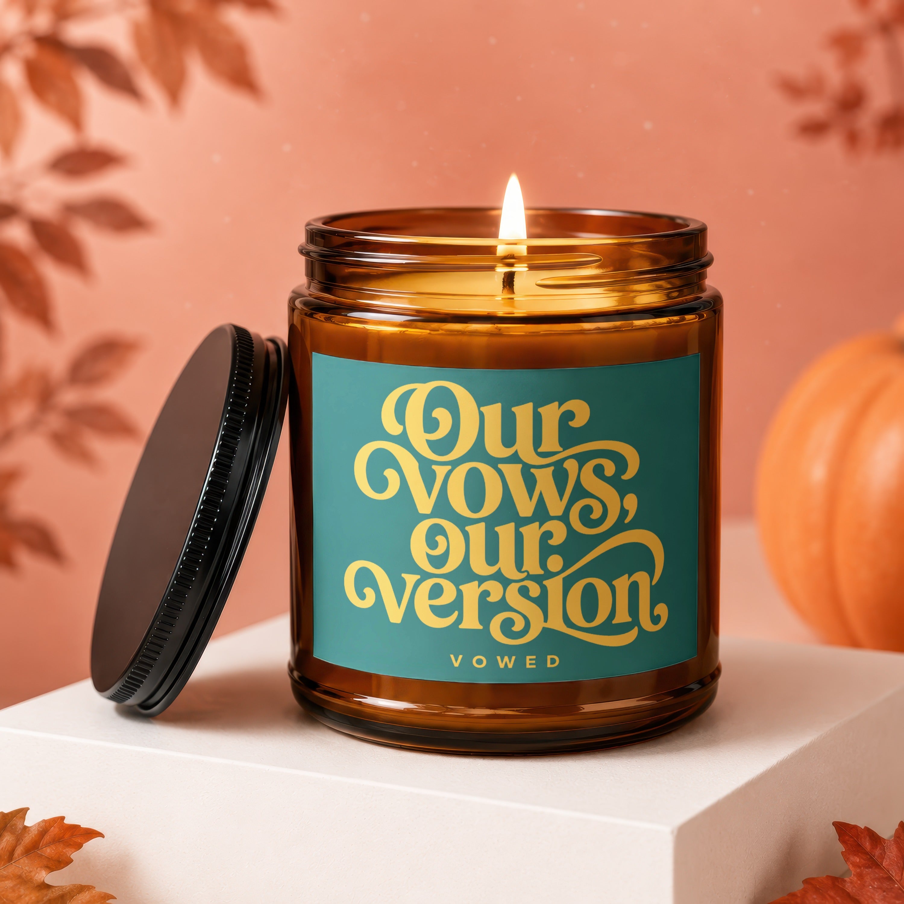 Amber glass candle with lit flame, teal label reads "Our Vows, Our Version".