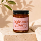 Candle labeled "Smells Like Bridesmaid Energy, Proven, Tested, Depleted, Vowed".