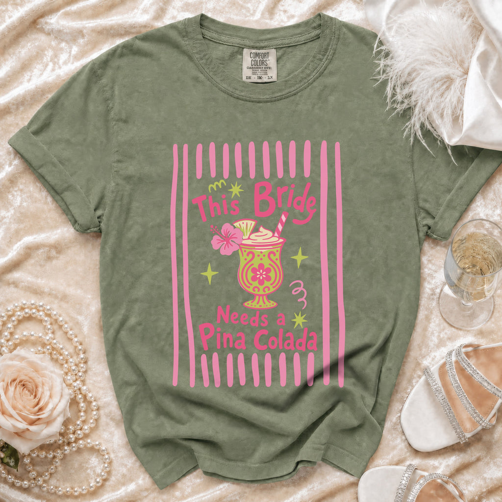 Olive green t-shirt with pink stripes, hibiscus flower, and "This Bride Needs a Pina Colada" text.