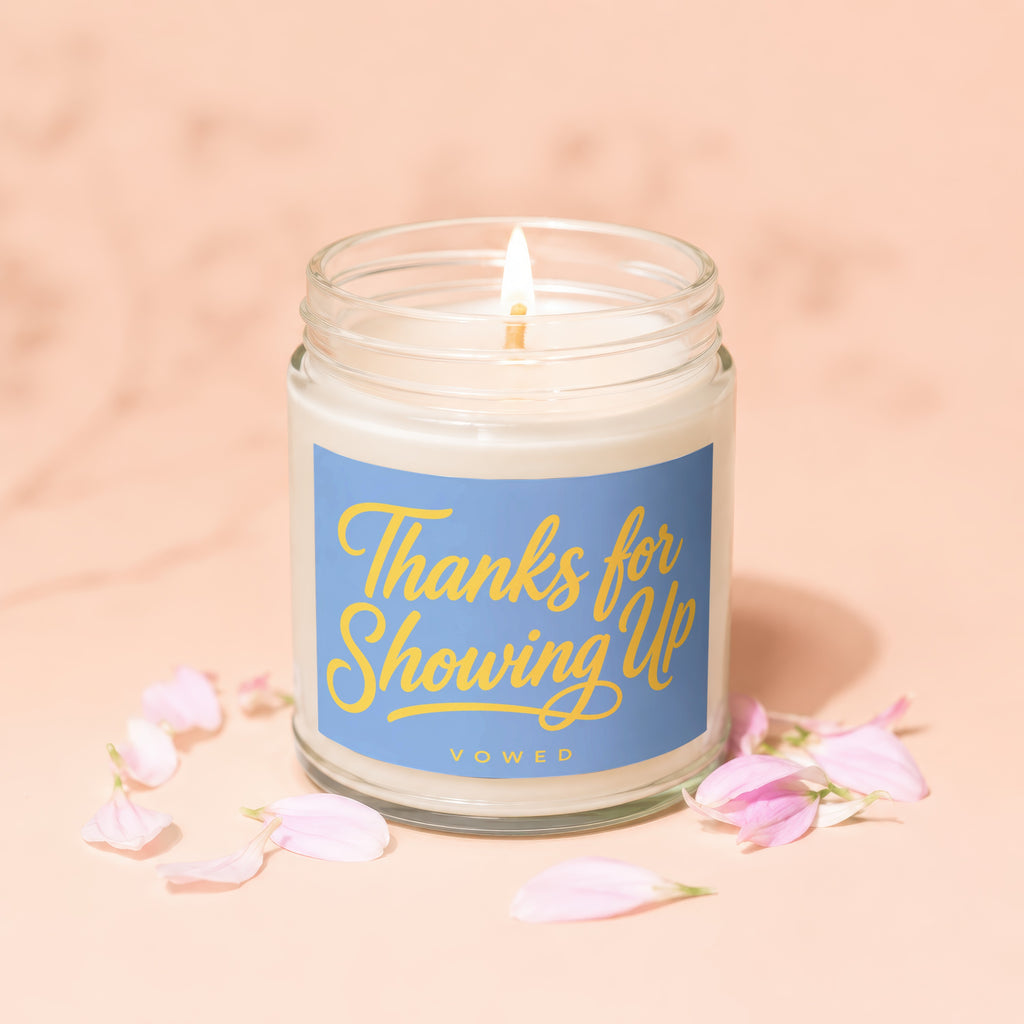 Lit candle in glass jar with blue label reading "Thanks for Showing Up".