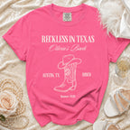 Pink t-shirt with "Reckless in Texas" text, cowboy boot, and disco ball.