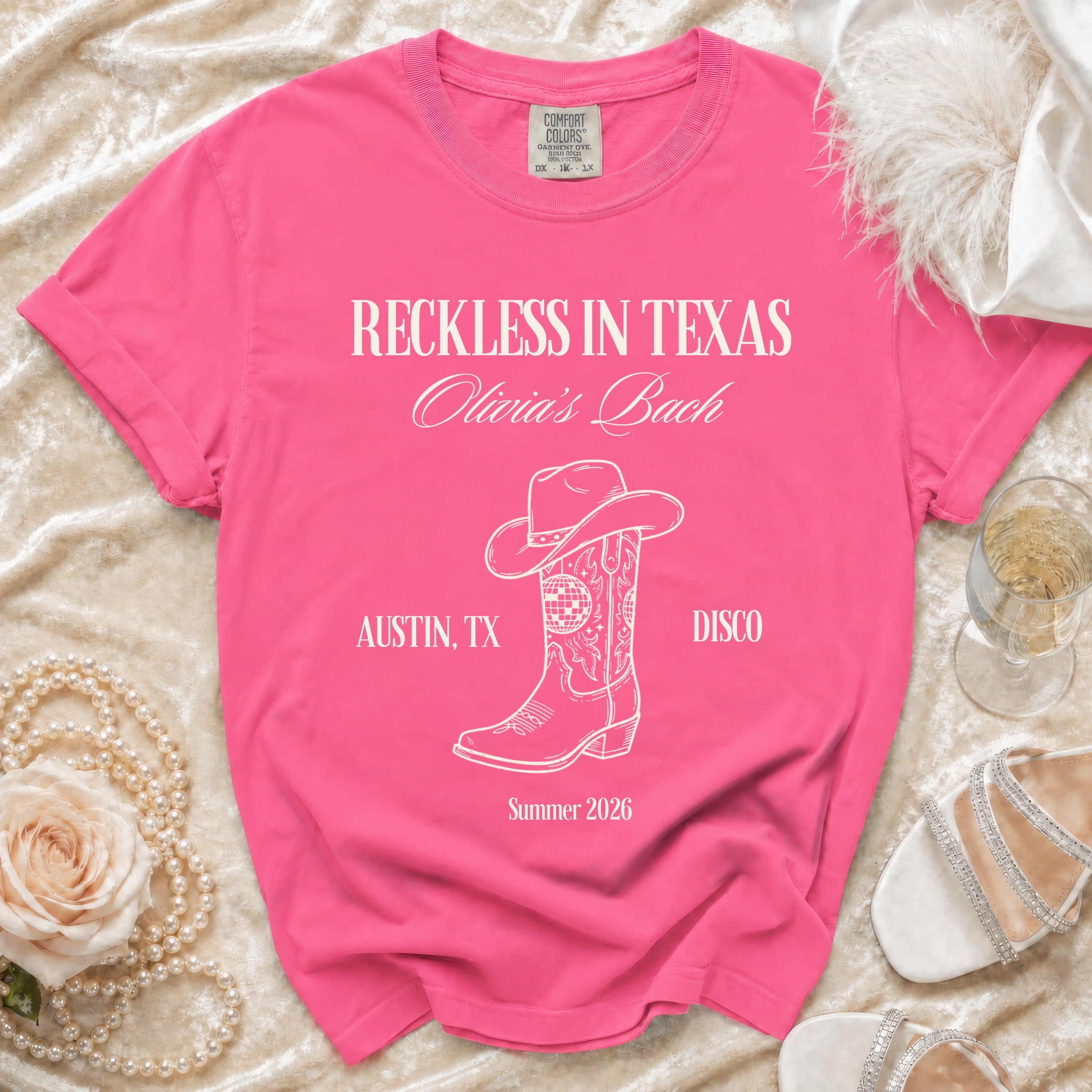 Pink t-shirt with "Reckless in Texas" text, cowboy boot, and disco ball.