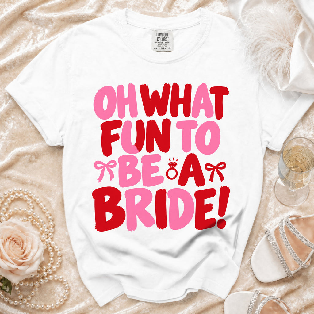 A white crewneck t-shirt with red and pink text reading OH WHAT FUN TO BE A BRIDE.