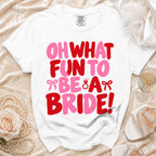 A white crewneck t-shirt with red and pink text reading OH WHAT FUN TO BE A BRIDE.