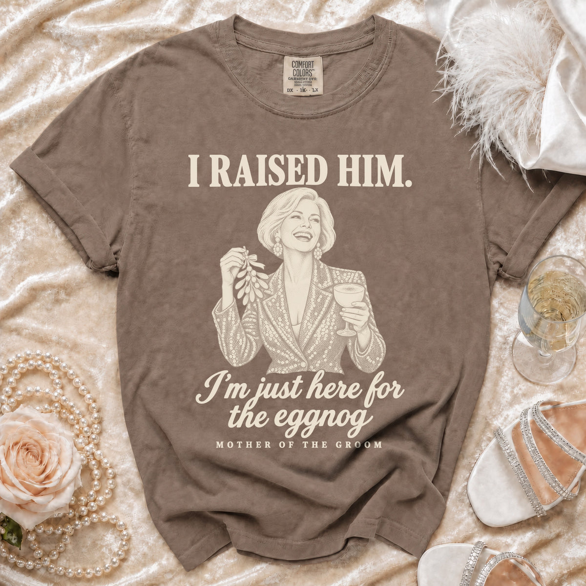 Brown crewneck t-shirt featuring a graphic of a woman holding mistletoe and eggnog with text.