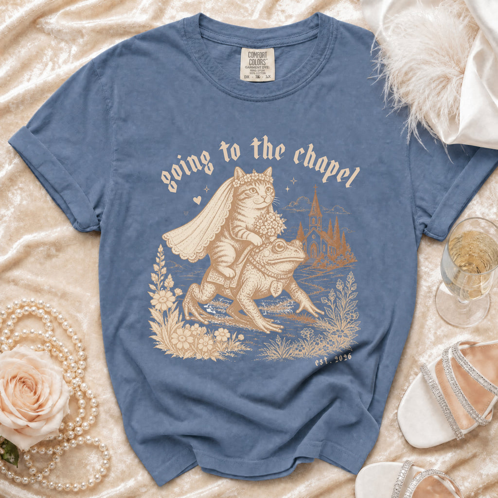 Blue t-shirt with a cat bride riding a frog with the text "going to the chapel est. 2026".