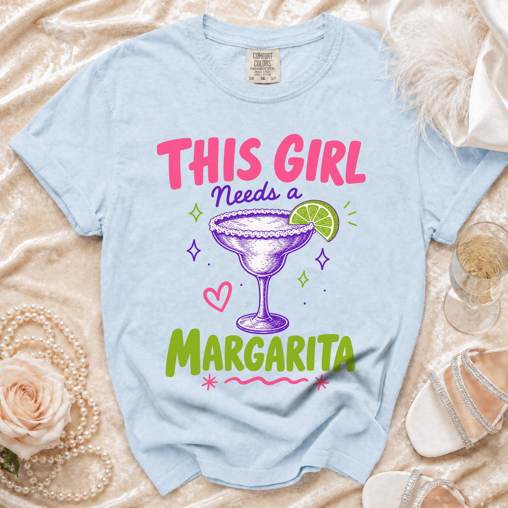 Light blue t-shirt with "This Girl Needs a Margarita" text and margarita graphic.