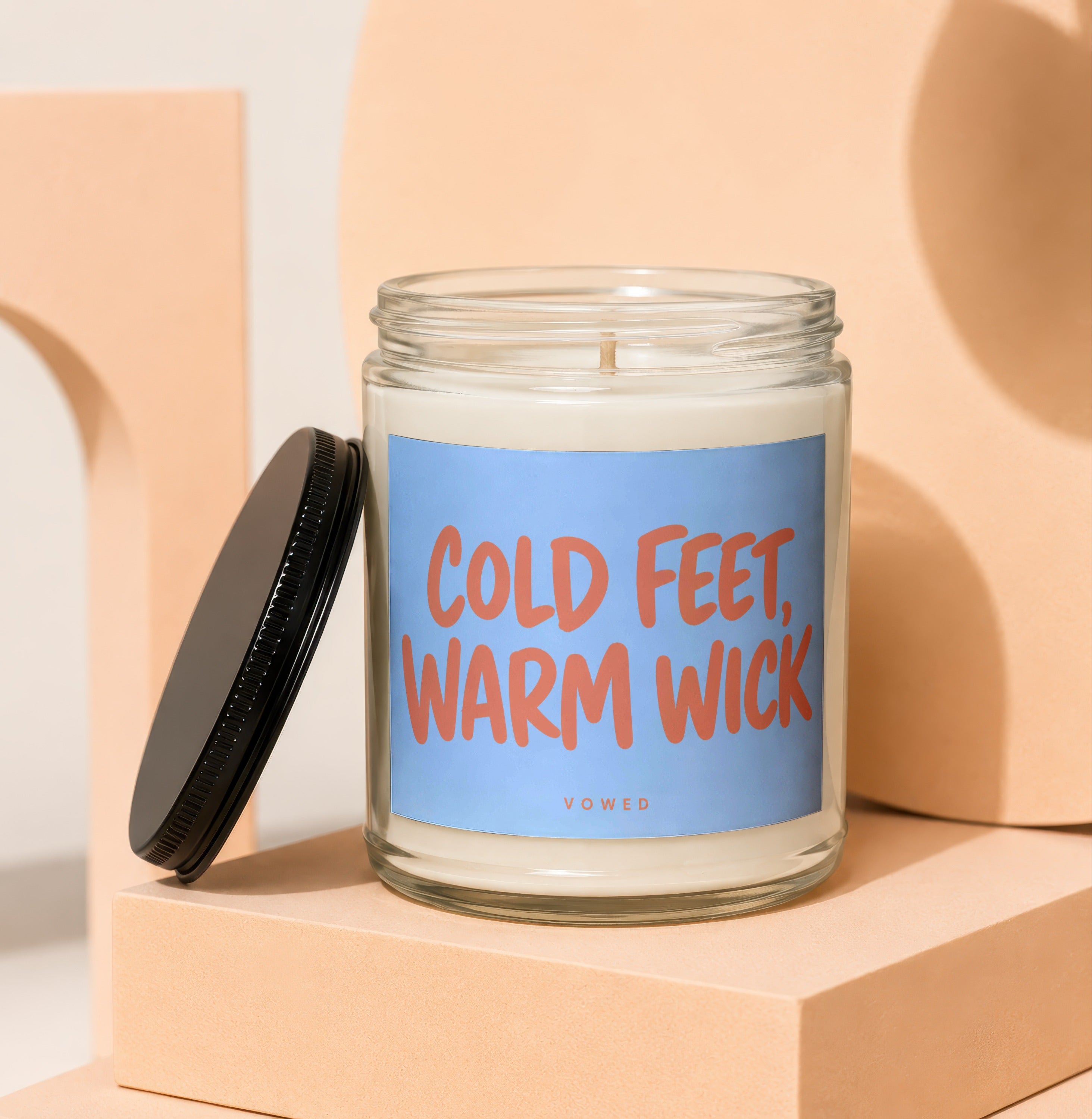 Glass candle with blue label saying "COLD FEET, WARM WICK" and "VOWED".