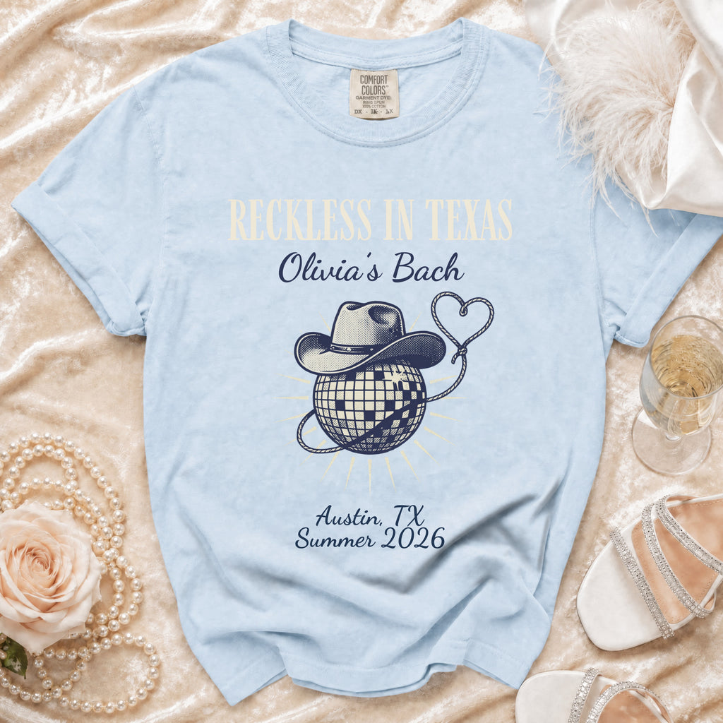 Light blue t-shirt with "Reckless in Texas Olivia's Bach" and disco ball graphic.