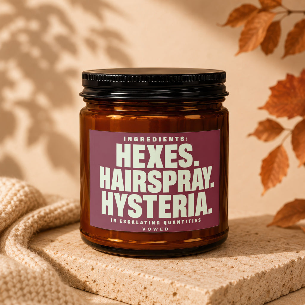 Brown glass jar with a maroon label that reads "Ingredients: Hexes. Hairspray. Hysteria. In Escalating Quantities. Vowed."