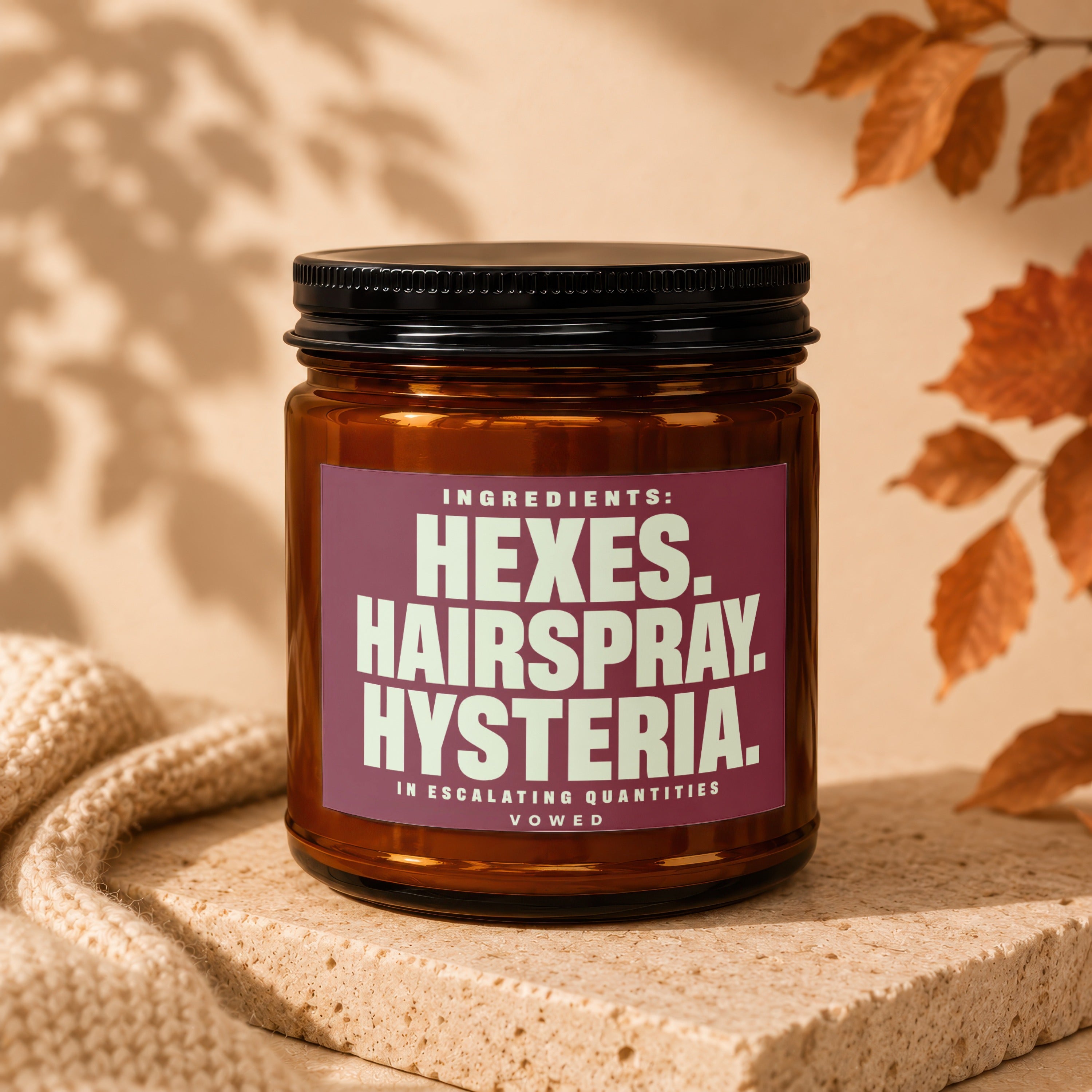 Brown glass jar with a maroon label that reads "Ingredients: Hexes. Hairspray. Hysteria. In Escalating Quantities. Vowed."
