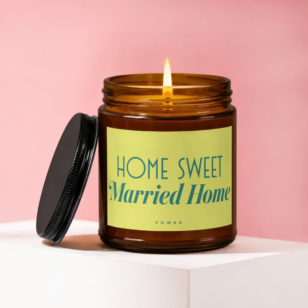 Amber candle with lit wick, black lid askew, and "HOME SWEET Married Home vowed" text.