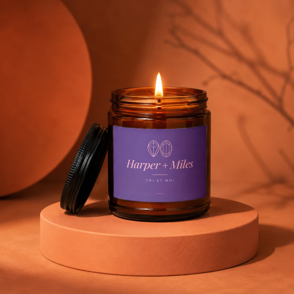 Harper + Miles "Toi et Moi" candle in amber glass jar with burning flame.
