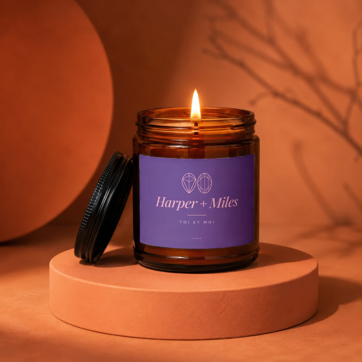 Harper + Miles "Toi et Moi" candle in amber glass jar with burning flame.