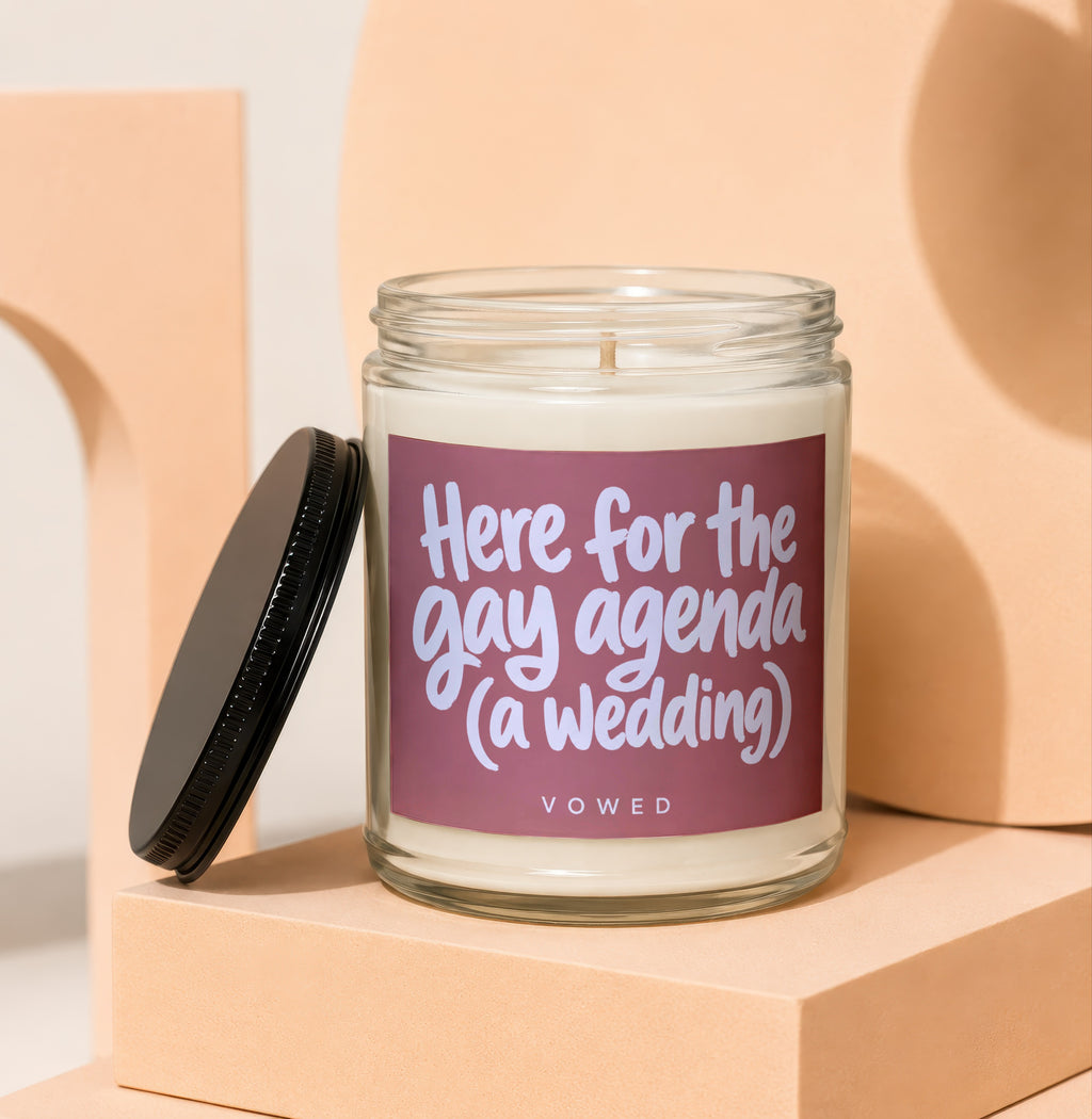 Candle with text "Here for the gay agenda (a wedding)" on a mauve label.