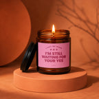 Amber jar candle lit with pink label that reads "Light me when I'm still waiting for your yes."