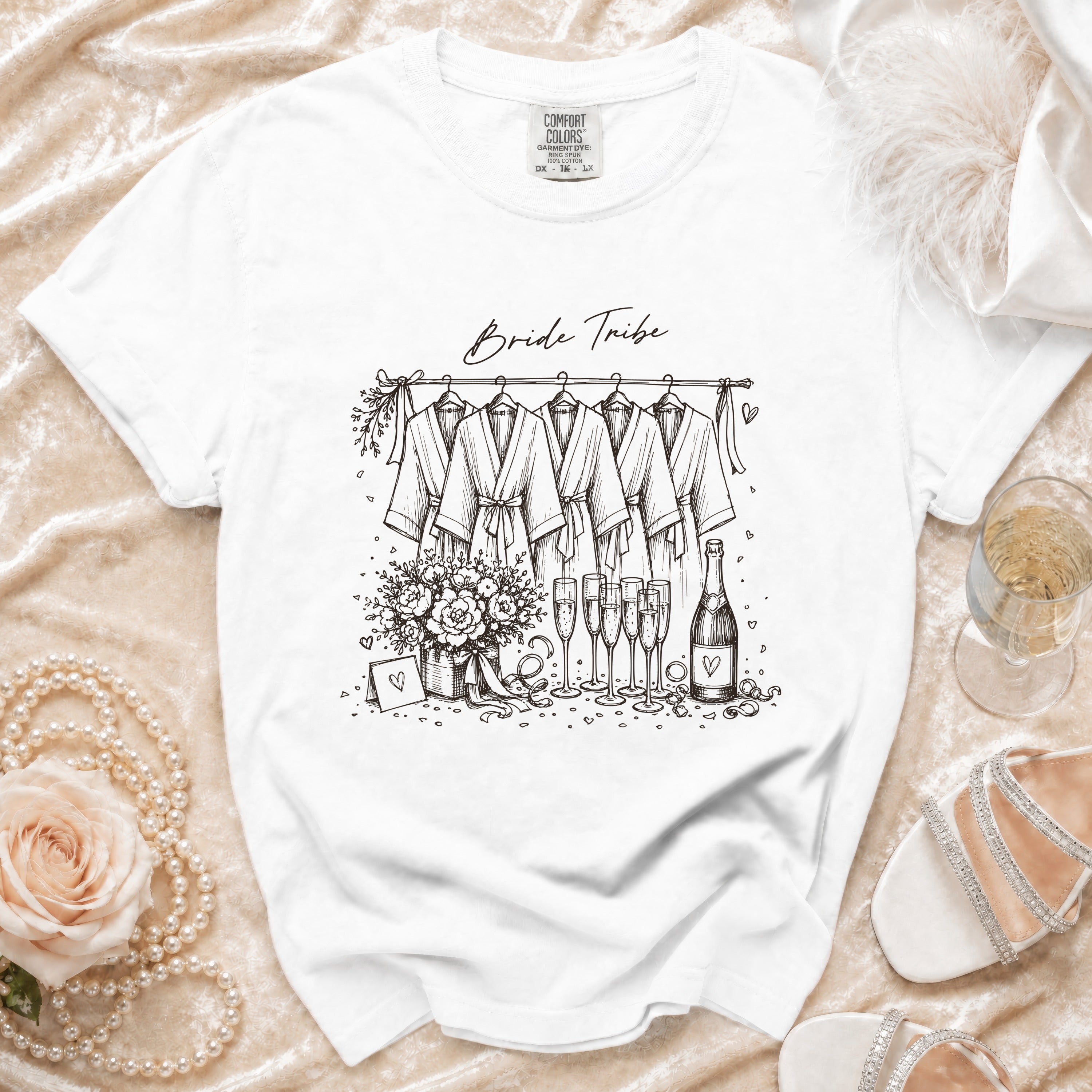 White t-shirt with "Bride Tribe" text and sketch of robes, flowers, and champagne.