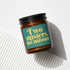 Amber glass candle with a teal label that reads "Two misters, no missus VOWED".