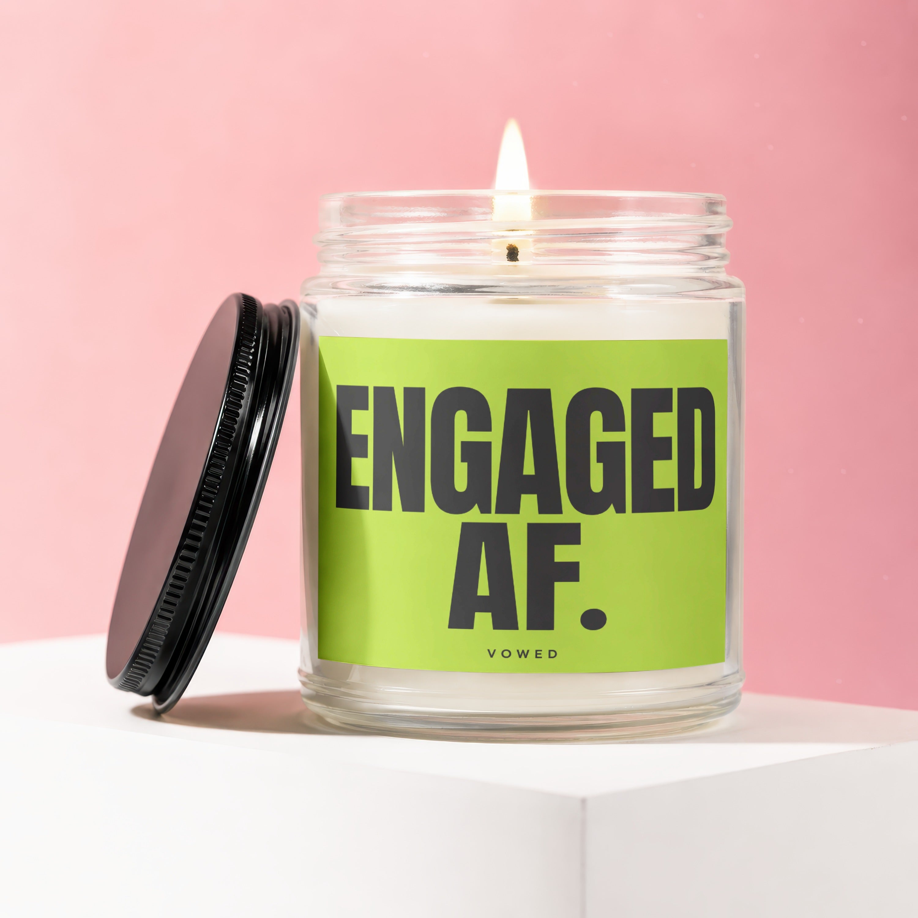 Lit glass candle with black lid, featuring green label with "ENGAGED AF." text.