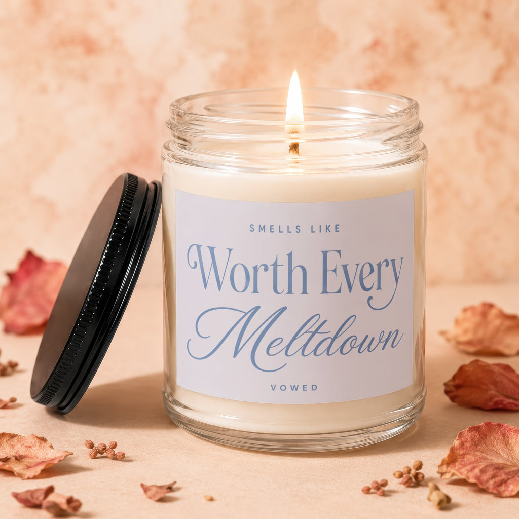 Lit candle in a glass jar with a black lid, saying "Sells Like Worth Every Meltdown".