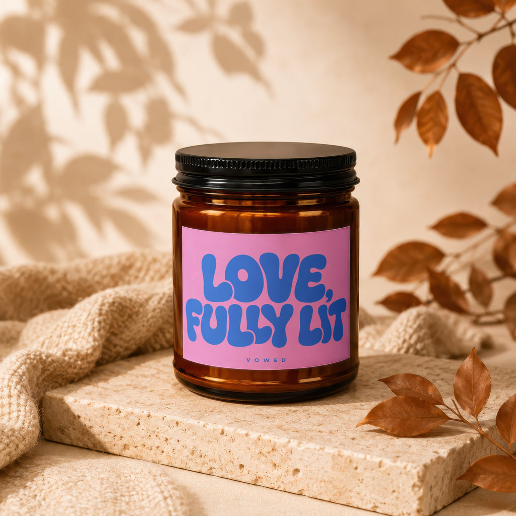 Amber jar candle with pink label reading "LOVE, FULLY LIT" and "VOWED" below.