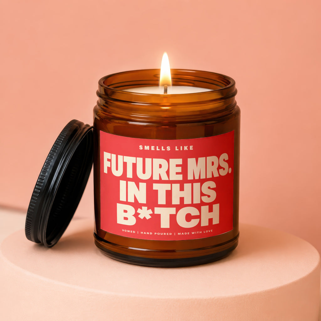 Amber jar candle with red label reading "Smells Like Future Mrs. In This B*tch".
