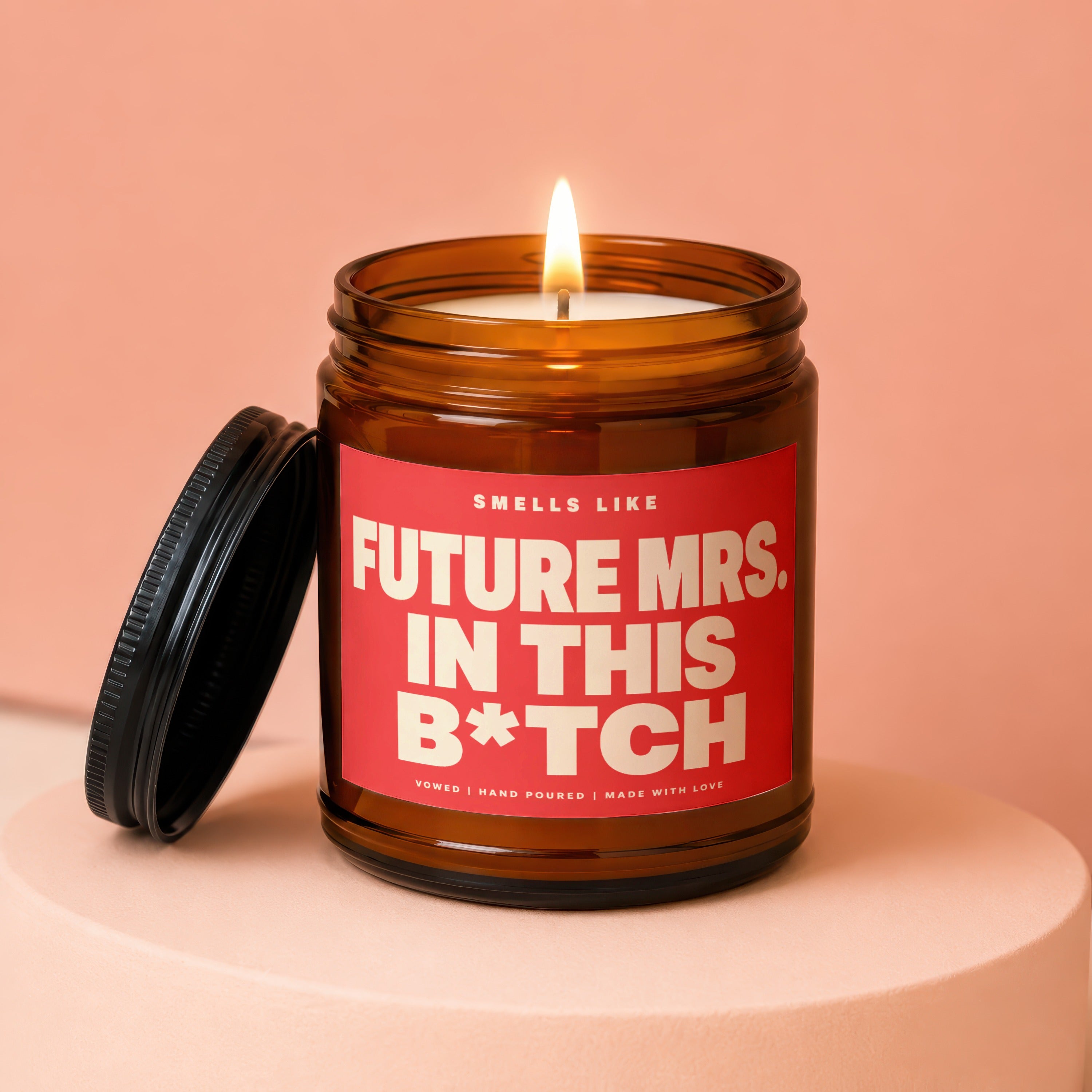 Amber jar candle with red label reading "Smells Like Future Mrs. In This B*tch".