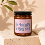 Candle with pink label reading "Smells Like He Finally Put a Ring On It" from Vowed Candle Co.