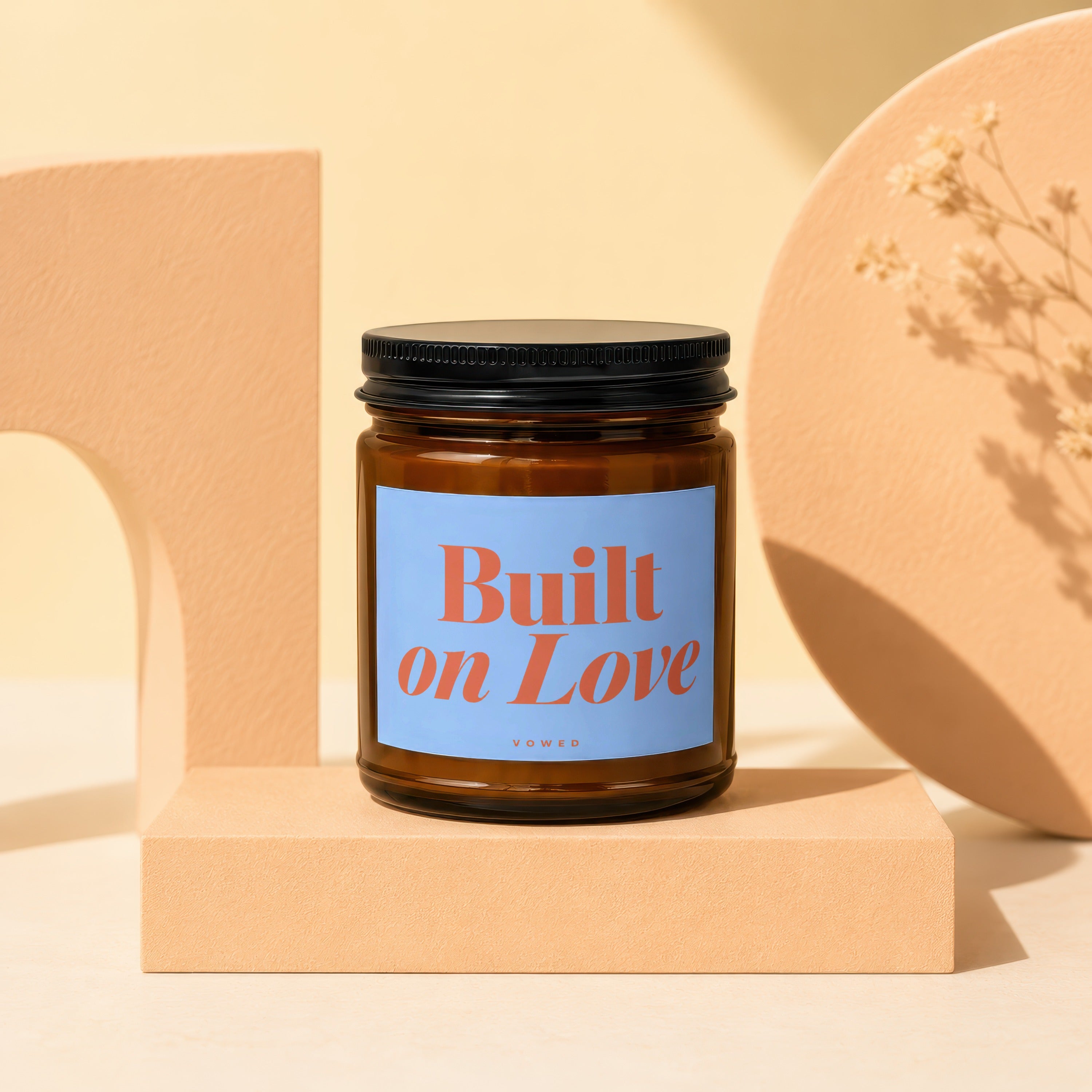 Brown glass candle with "Built on Love" on a blue label.