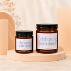 Two amber candles with black lids, labels read "Celebrating both dates."