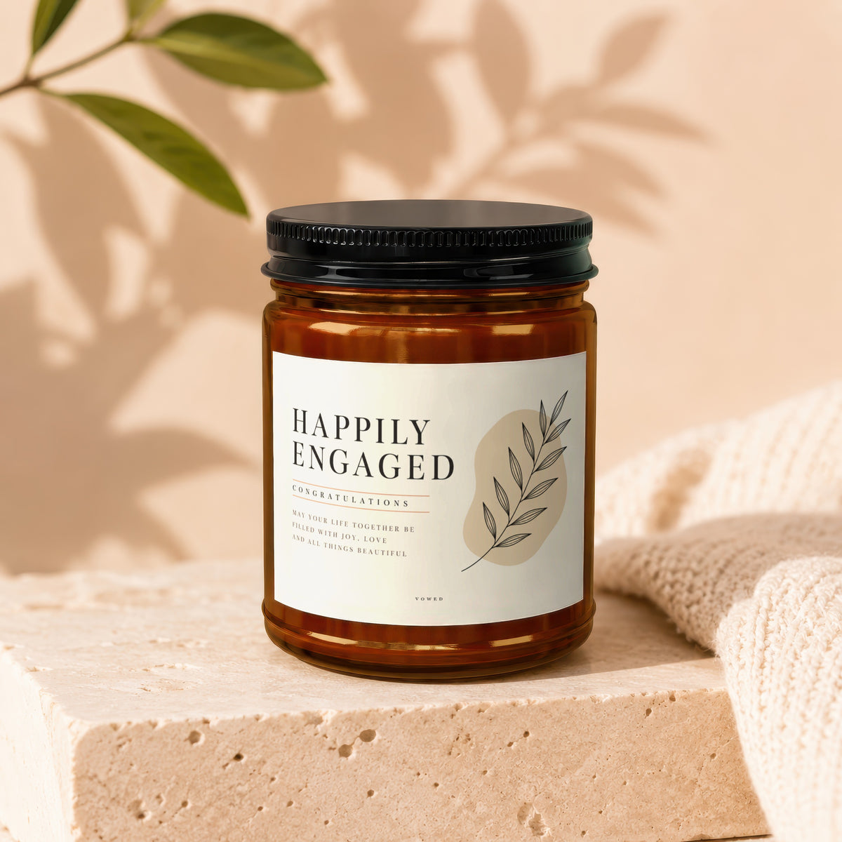Amber candle with "Happily Engaged" label and botanical illustration.