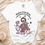 White t-shirt with graphic: skeleton with curlers, makeup, and coffee, reading "Mother of the Bride and Raising the Deadlines."