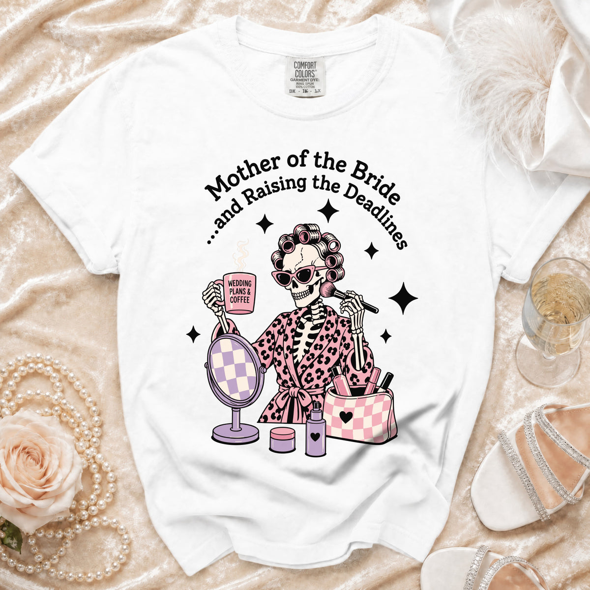 White t-shirt with graphic: skeleton with curlers, makeup, and coffee, reading "Mother of the Bride and Raising the Deadlines."