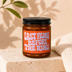 Amber candle in glass jar with orange label that reads "LAST FLING BEFORE THE RING".