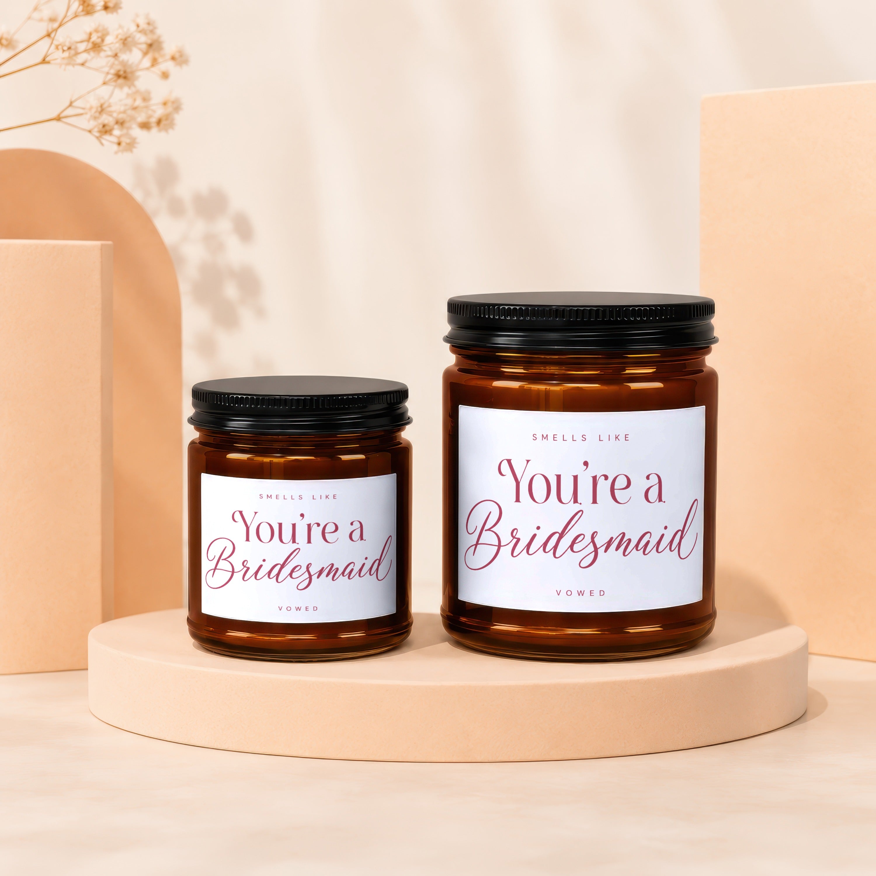 Two amber glass candles, one large and one small, with white labels reading "You're a Bridesmaid".
