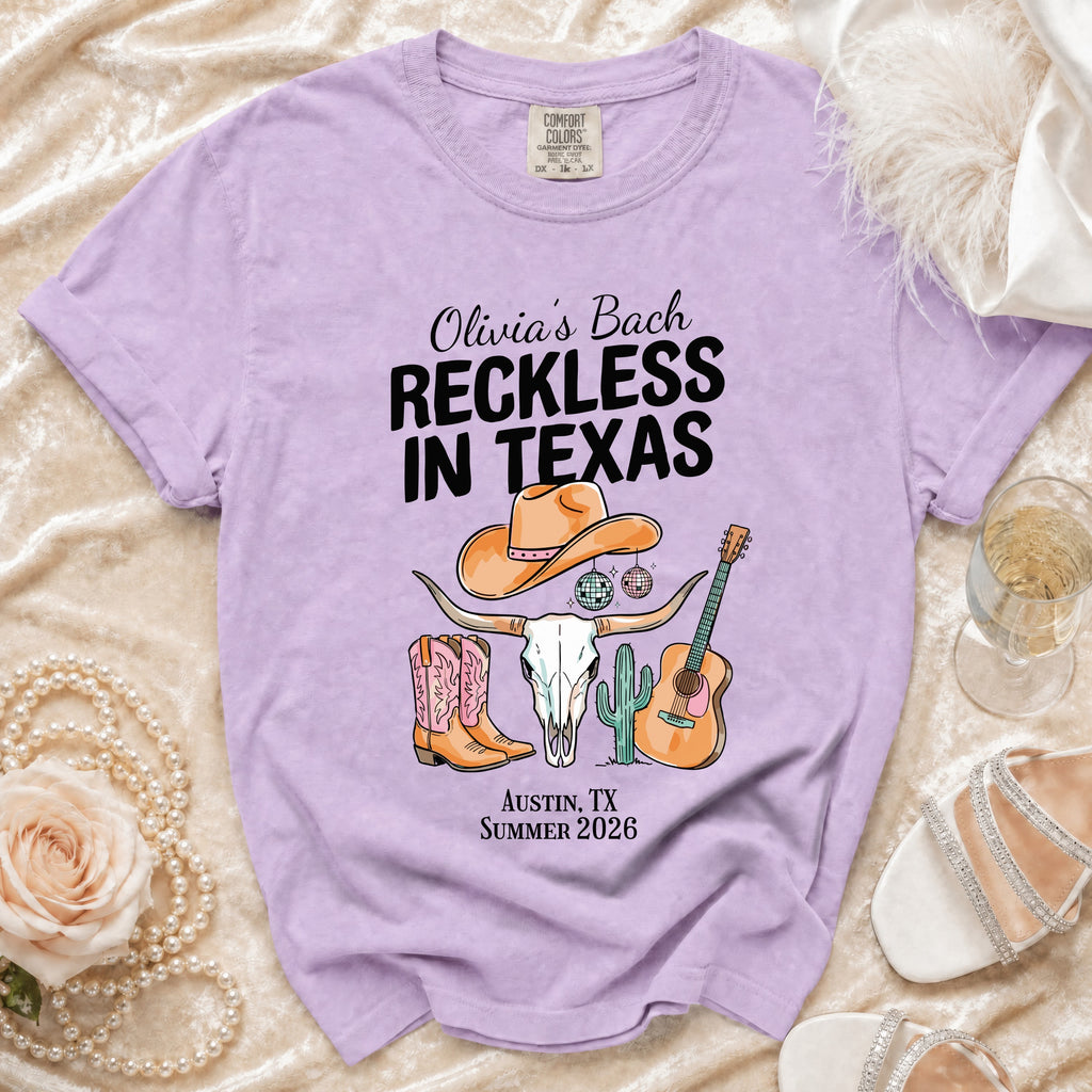 Lavender t-shirt graphic with cowgirl boots, bull skull, and guitar for "Olivia's Bach Reckless in Texas".