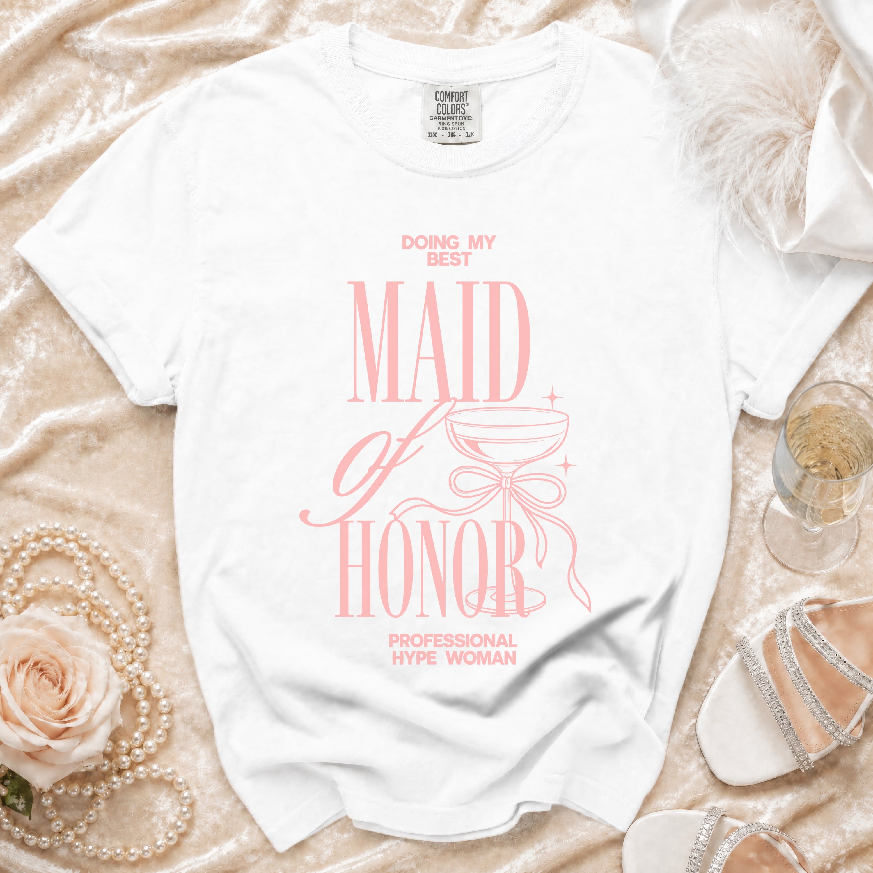 White t-shirt with pink text "MAID OF HONOR" and "PROFESSIONAL HYPE WOMAN".
