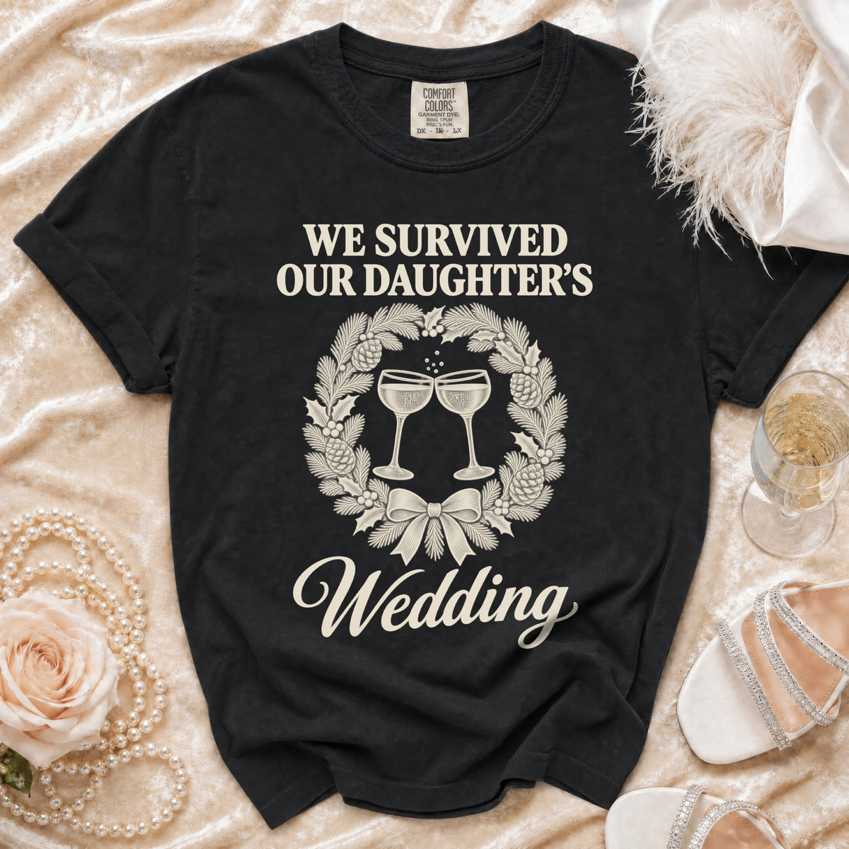 A black t-shirt featuring a Christmas wreath graphic and the text We Survived Our Daughter's Wedding.