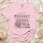 Pink t-shirt with "Bride Tribe" and sketch of robes, flowers, champagne, and bottle.