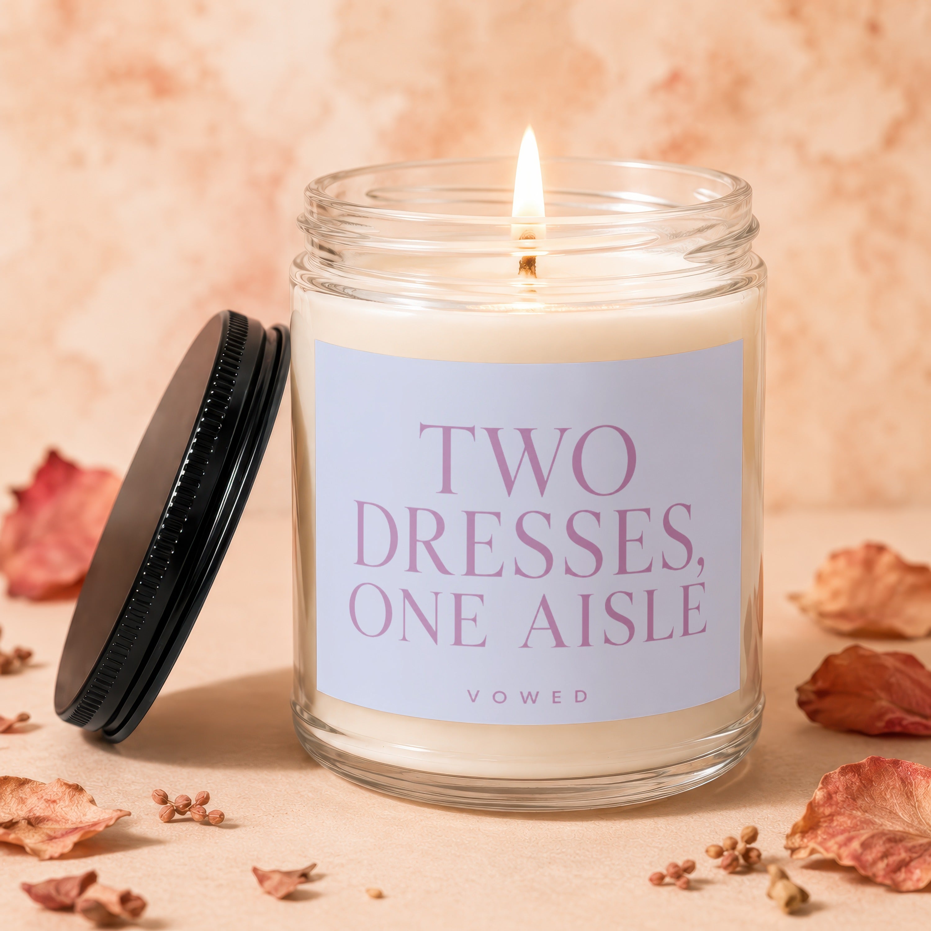 Candle with "Two Dresses, One Aisle" text and a lit wick.