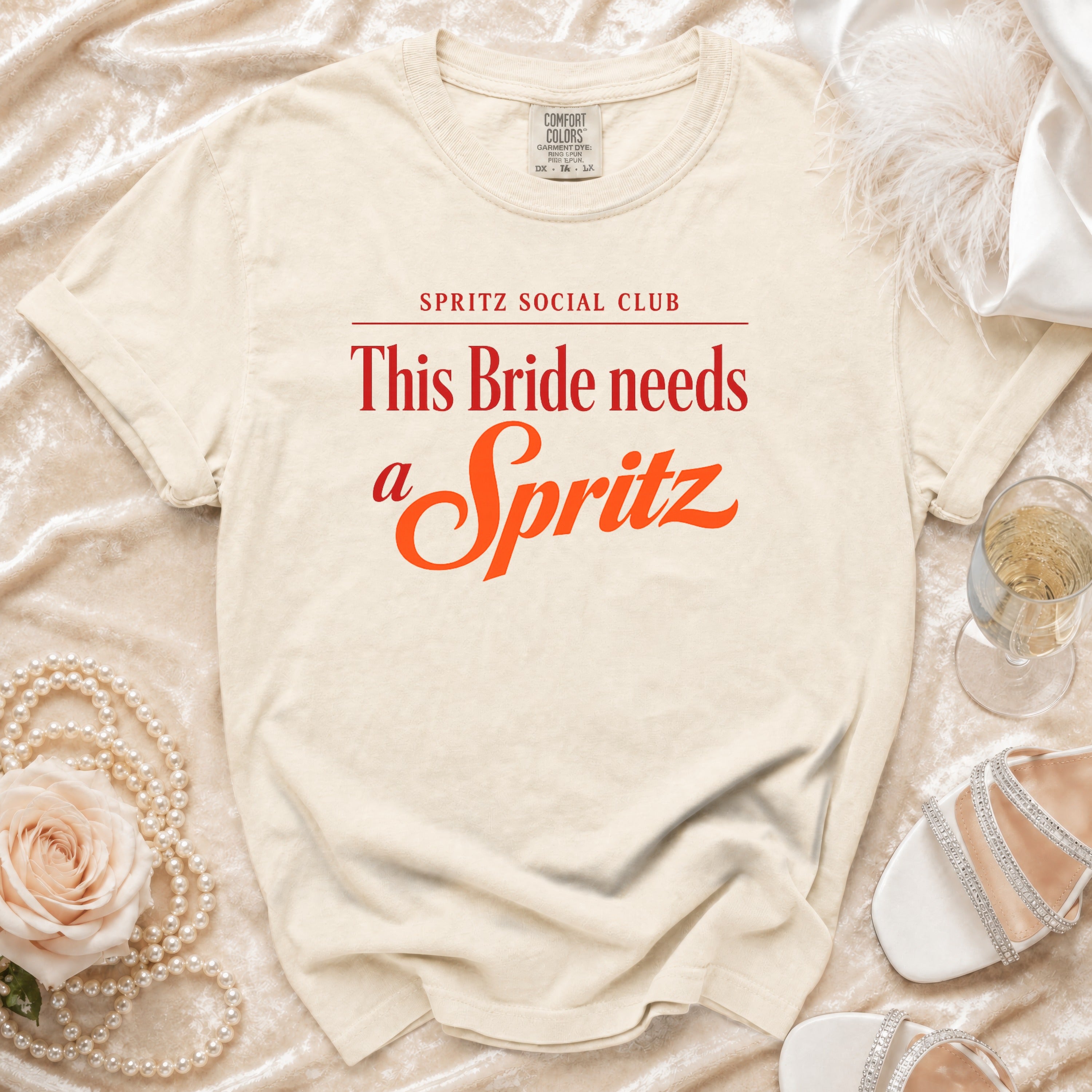 Cream t-shirt with "Spritz Social Club" and "This Bride needs a Spritz" in red.