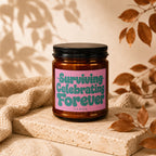 Brown glass candle with pink label. Text reads "Surviving Celebrating Forever Vowed".