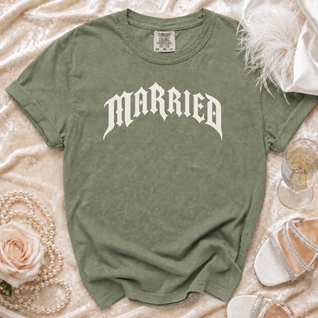 Olive green t-shirt with "MARRIED" in gothic font, laid flat with accessories.