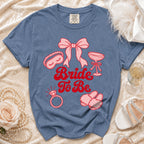Blue t-shirt with pink "Bride To Be" text and bridal icons.