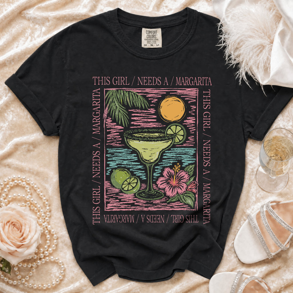 Black t-shirt with text "This girl needs a margarita" and margarita graphic.