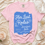 Pink t-shirt with "Her Last Rodeo" text, cowboy boots, and hat.