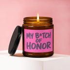 Amber jar candle with a lit wick and pink label reading "My B*tch of Honor".