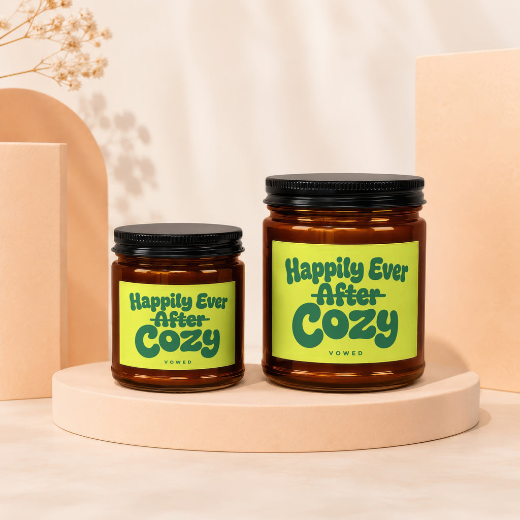 Two amber glass jars with black lids, one larger, featuring "Happily Ever After Cozy" labels.