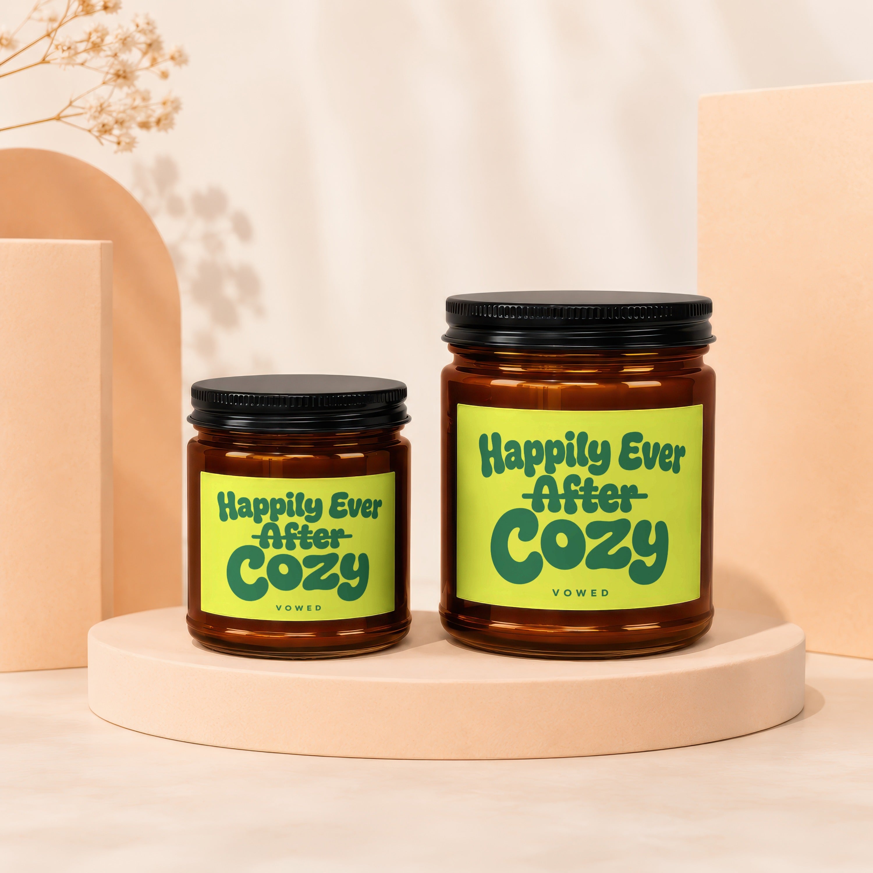 Two amber glass jars with black lids, one larger, featuring "Happily Ever After Cozy" labels.